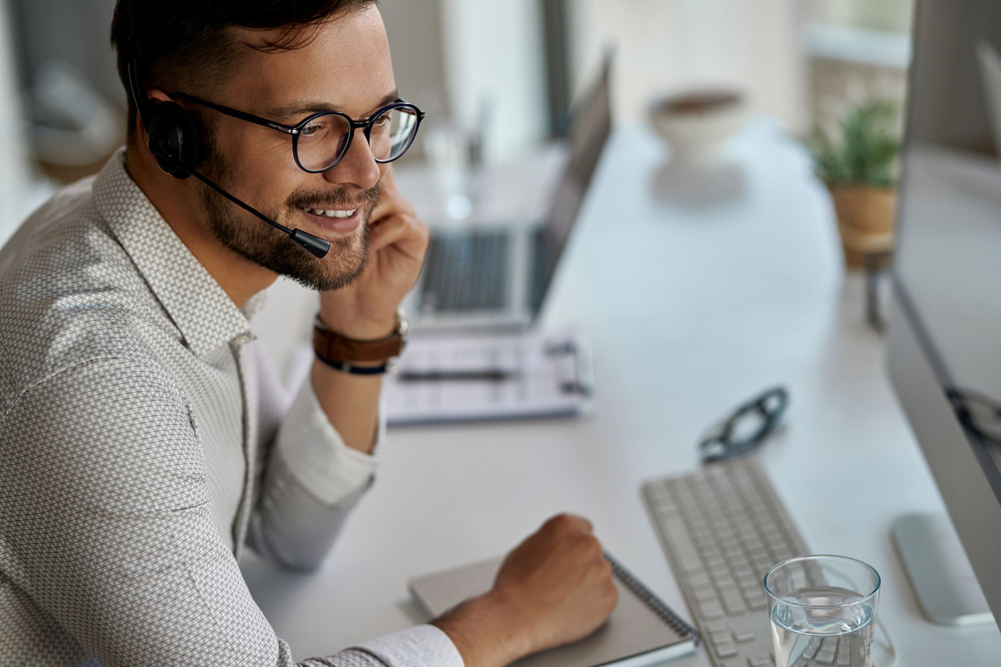 Young, happy customer service representative working as IT support remotely