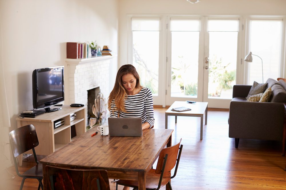 Woman sat at table working from home using a hosted desktop